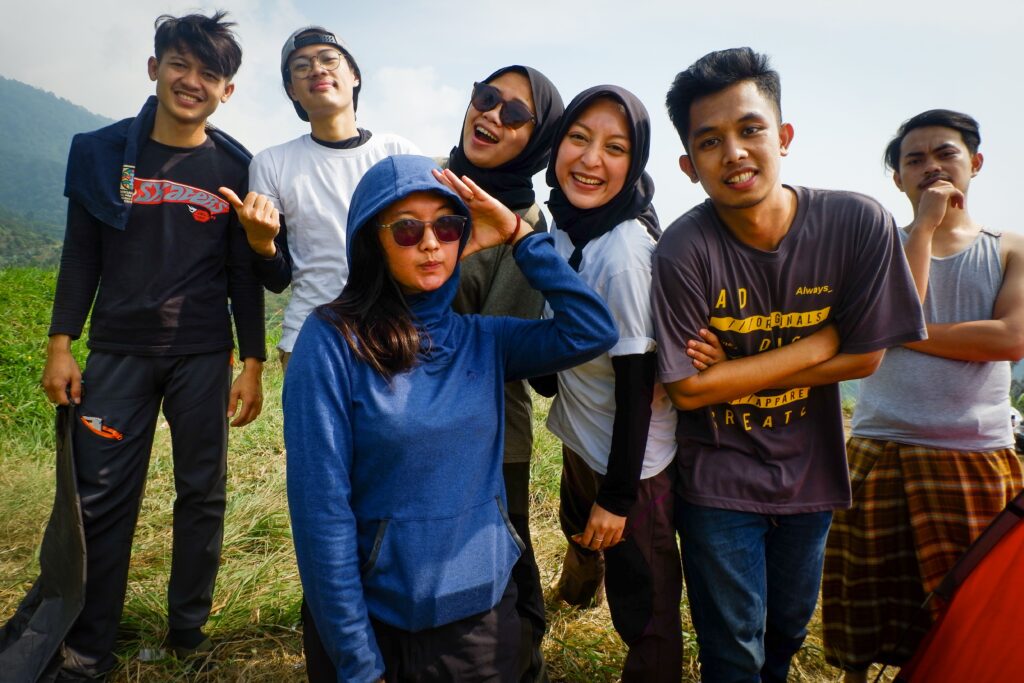 A group of teenagers laughing and posing on a sunny outdoor adventure trip.