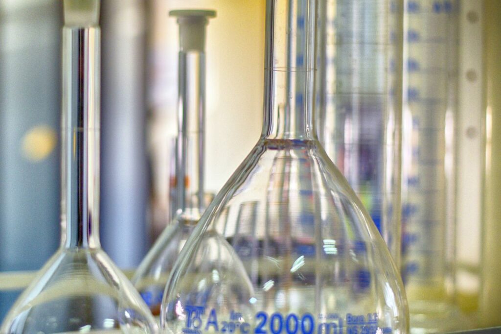 Closeup of various glass transparent chemistry flasks placed on table in modern laboratory