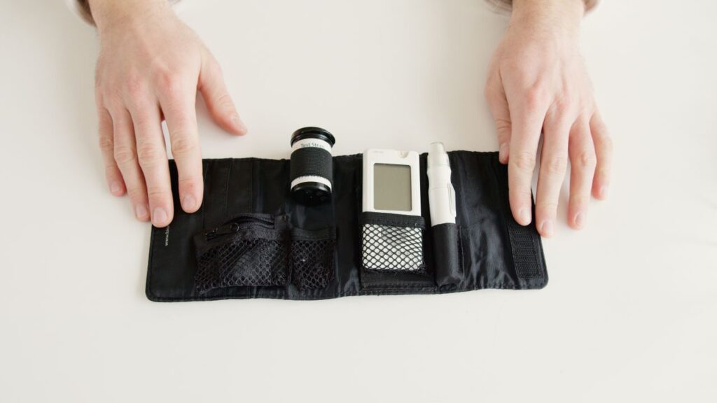Close-up of hands holding a diabetic glucometer kit on a white table for blood sugar testing.