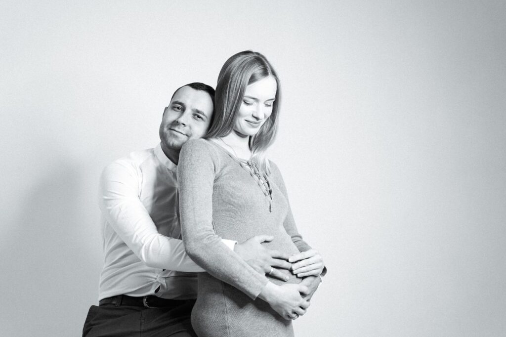 A loving couple shares a tender embrace, highlighting their anticipation of parenthood.